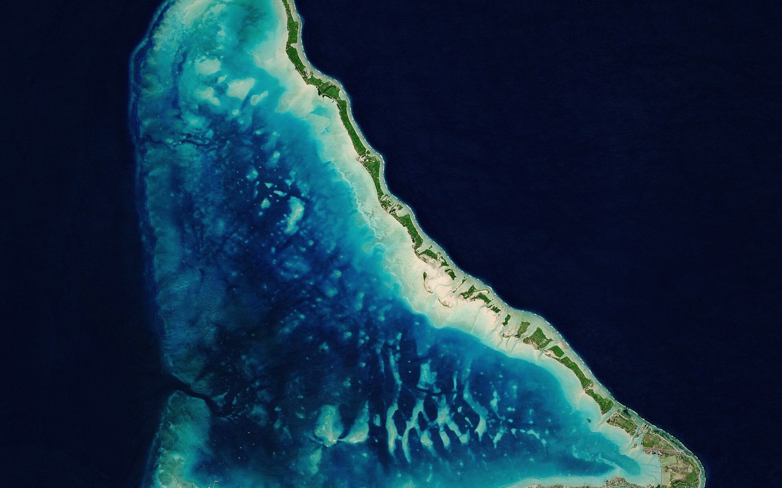 A causeway at low tide with a lagoon on one side and open ocean on the other