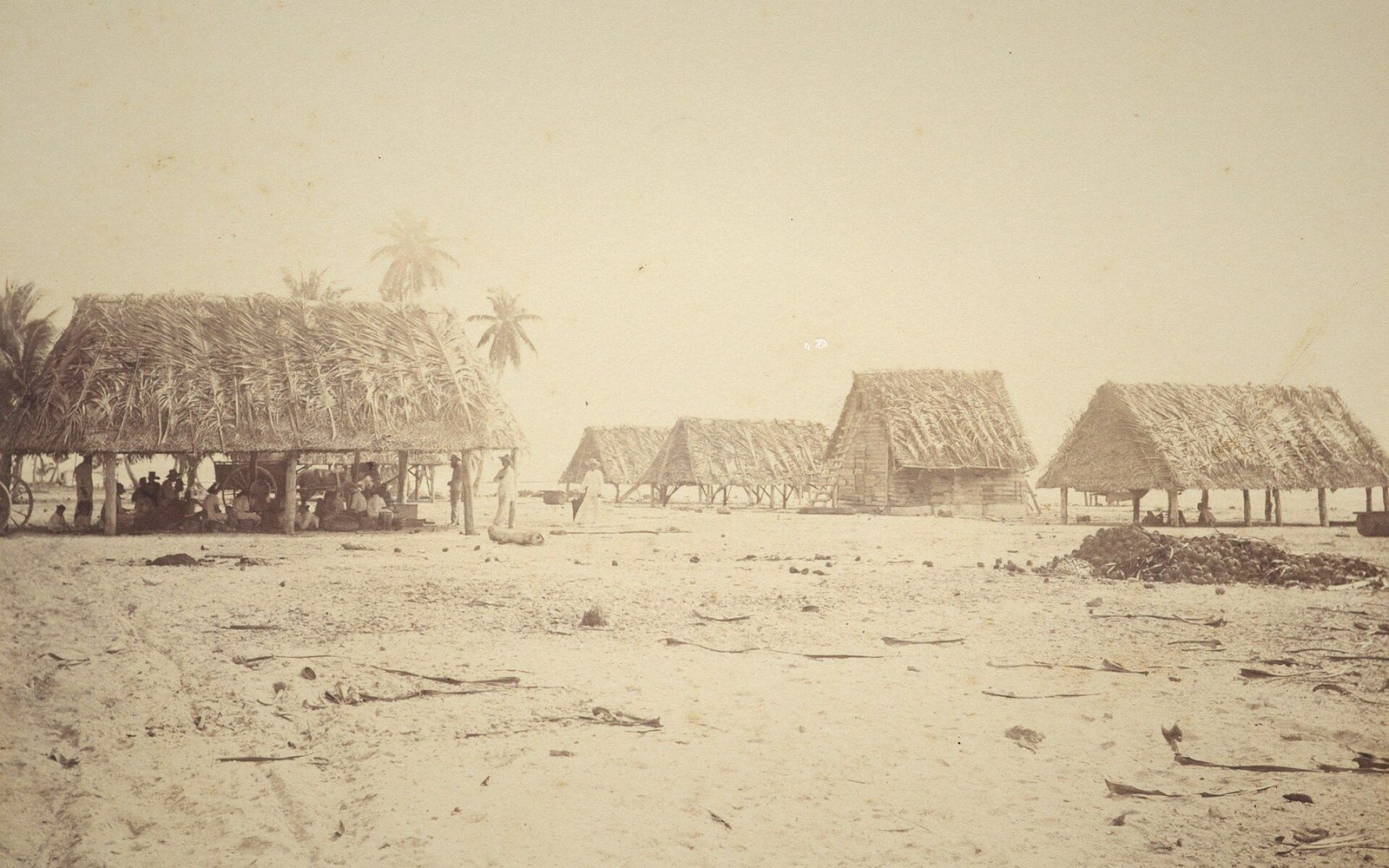 A copra shed with sacks and drying racks, adult workers at work, no minors
