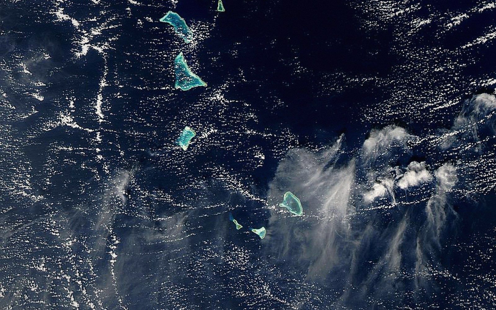 Satellite view of scattered turquoise coral atolls in the Gilbert Islands amid dark ocean waters